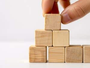 Hand putting and stacking blank wooden cubes on table