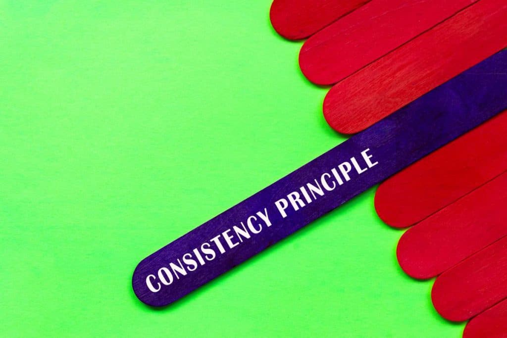 Consistency principle text on purple color wooden stick